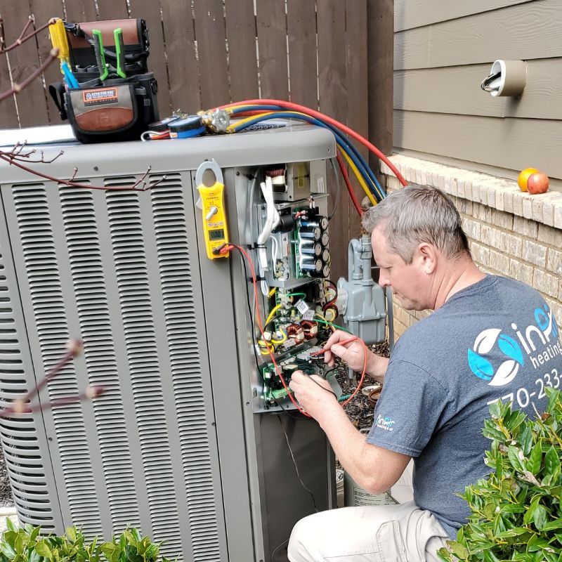 A technician services the internal components of a large outdoor air conditioning unit providing top-rated air conditioning repair & replacement services!