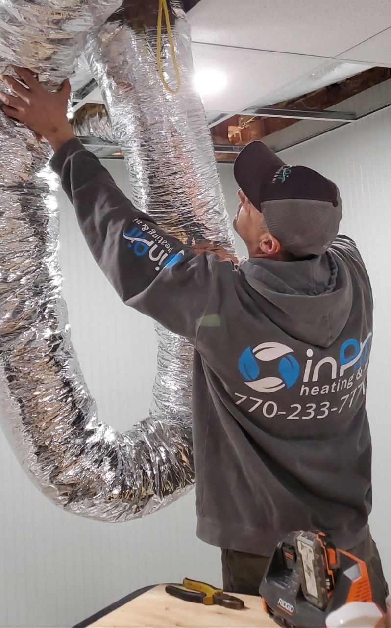 A technician expertly installing ductwork in a building's ceiling area.