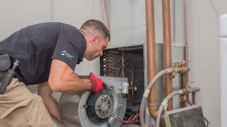 A technician repairs a furnace, focused on furnace replacement, with tools on hand.