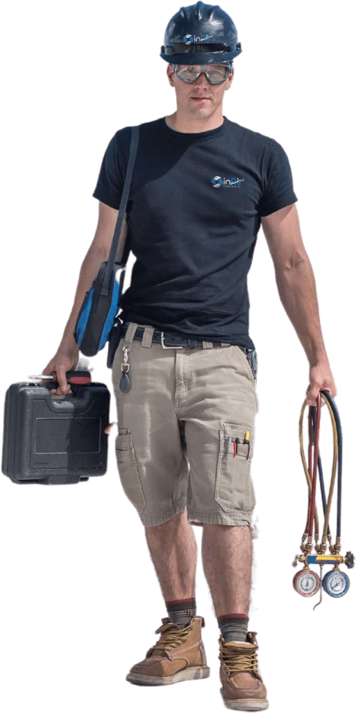 A worker wearing a black helmet, black t-shirt, beige cargo shorts, and brown boots carries a black toolbox and a set of pressure gauges, ready to tackle any home repair needs.