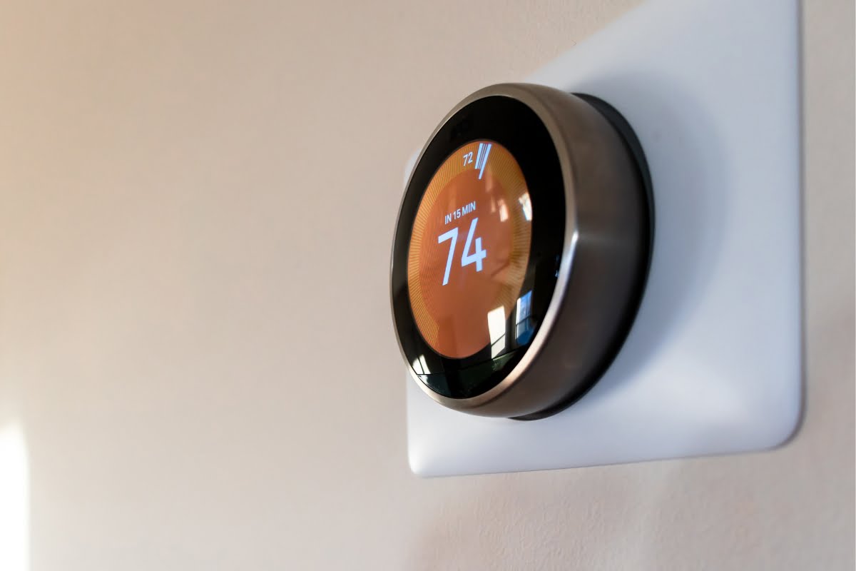 A smart thermostat mounted on a wall displays a temperature of 74 degrees Fahrenheit on its digital screen, seamlessly integrating with the energy-efficient HVAC system.