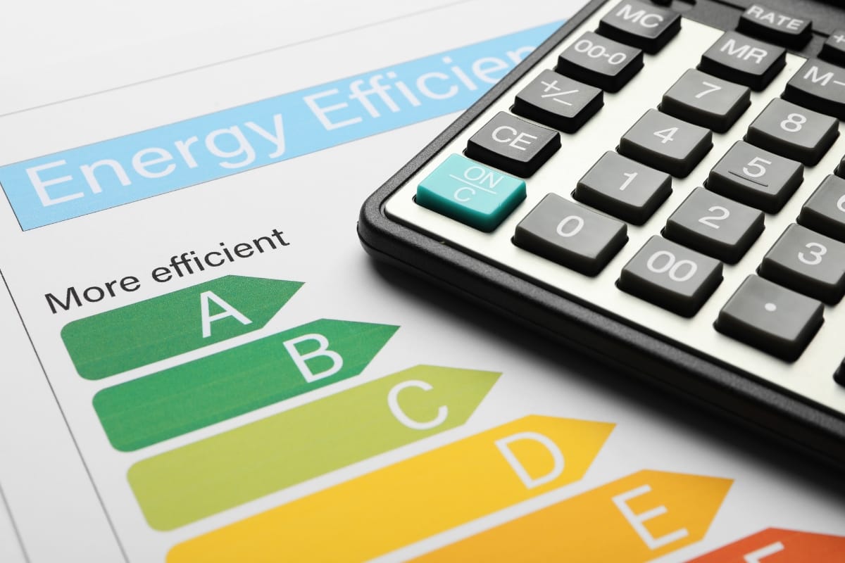 A calculator rests on a paper displaying an energy efficiency chart with ratings from A to E, essential for planning HVAC fall maintenance, where A signifies the highest efficiency.