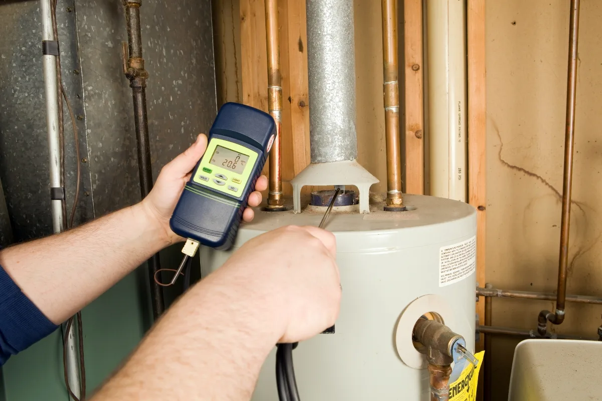 A person uses a digital meter to test gas emissions from a water heater, ensuring it operates efficiently without the common heat pump issues often encountered in modern systems.
