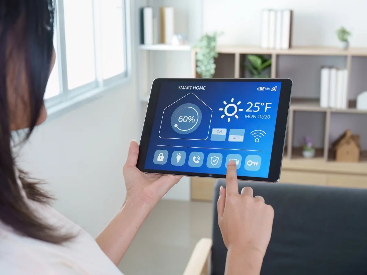 A person uses a tablet to control smart home settings, displaying temperature, security, and devices—showcasing popular home renovation trends Atlanta homeowners love, with the temperature set to 25°F and system power at 60%.
